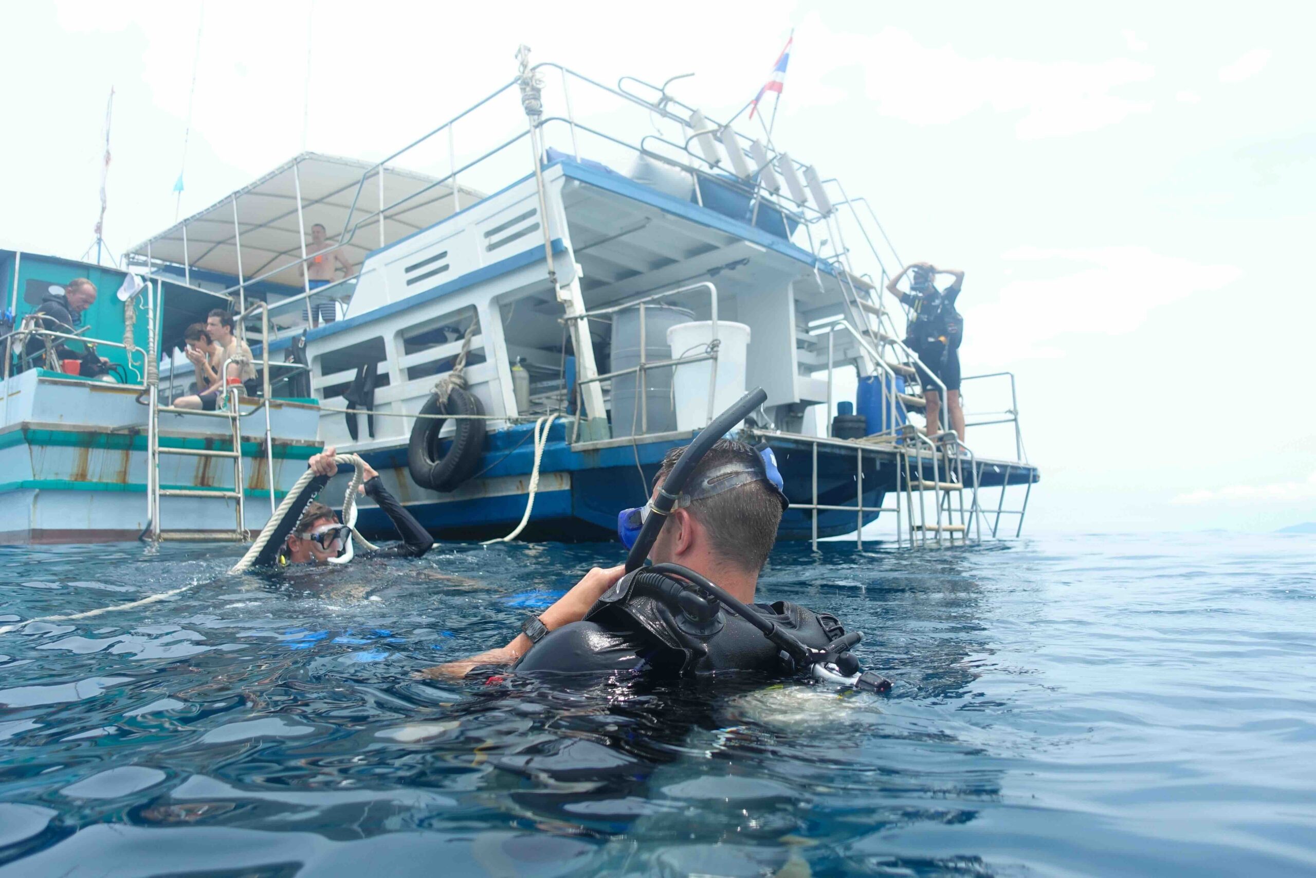 “Two scuba divers descending next to a dive boat at Sail Rock in the Gulf of Thailand.”