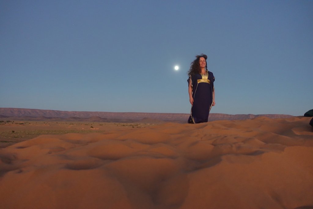 Pilar wearing a Moroccan dress with the Full Moon on the background at sunset time. Tinfou dunes