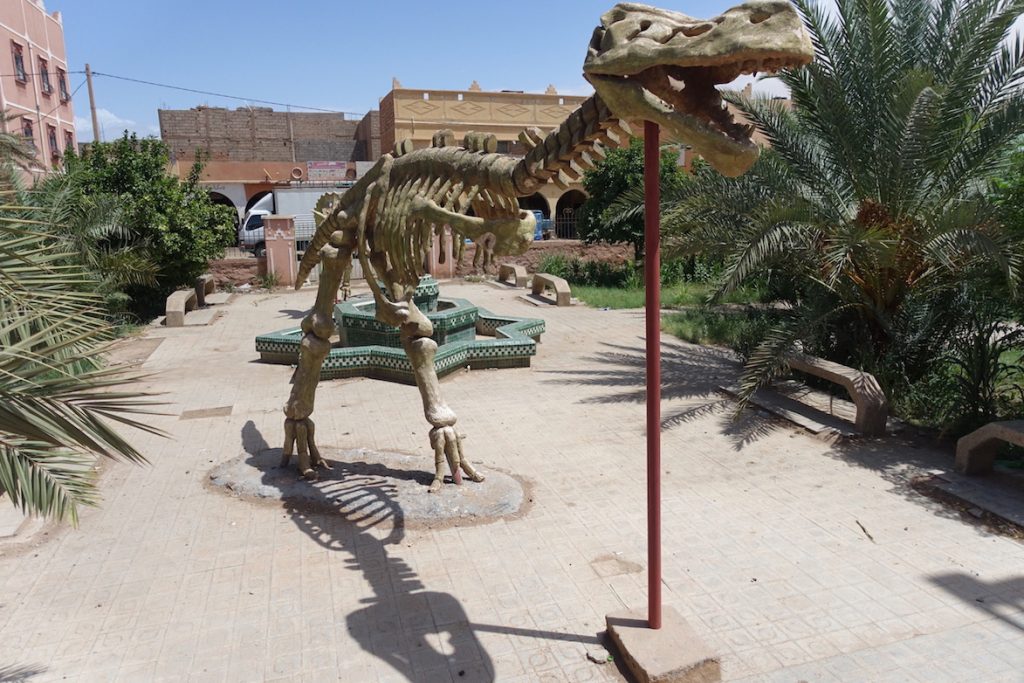 Dinosaur at the dinosaur park in Zagora. Some buildings on the background.