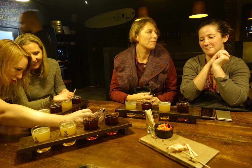 Four girls trying four types of different beers with snacks