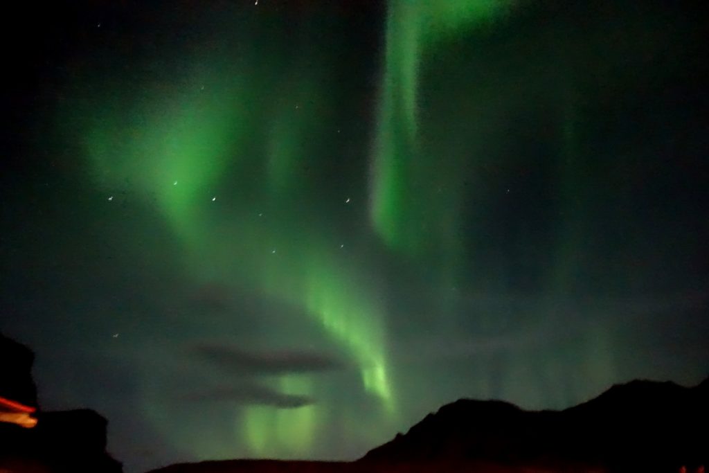 Green aurora borealis over some hills in Vike Iceland