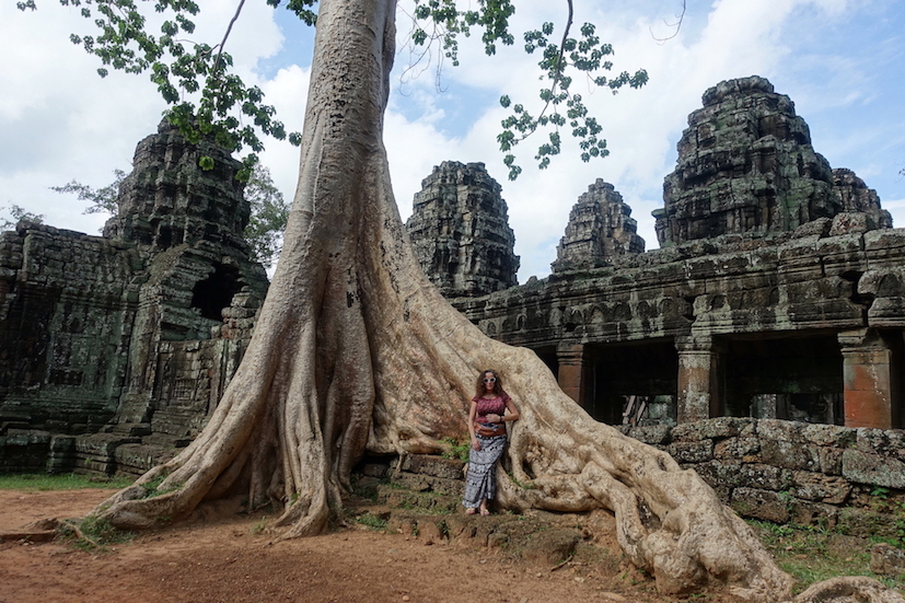 Pilar leaning on a Banyan tree and the Angkor Wat temple of Bantei Kdei on the back