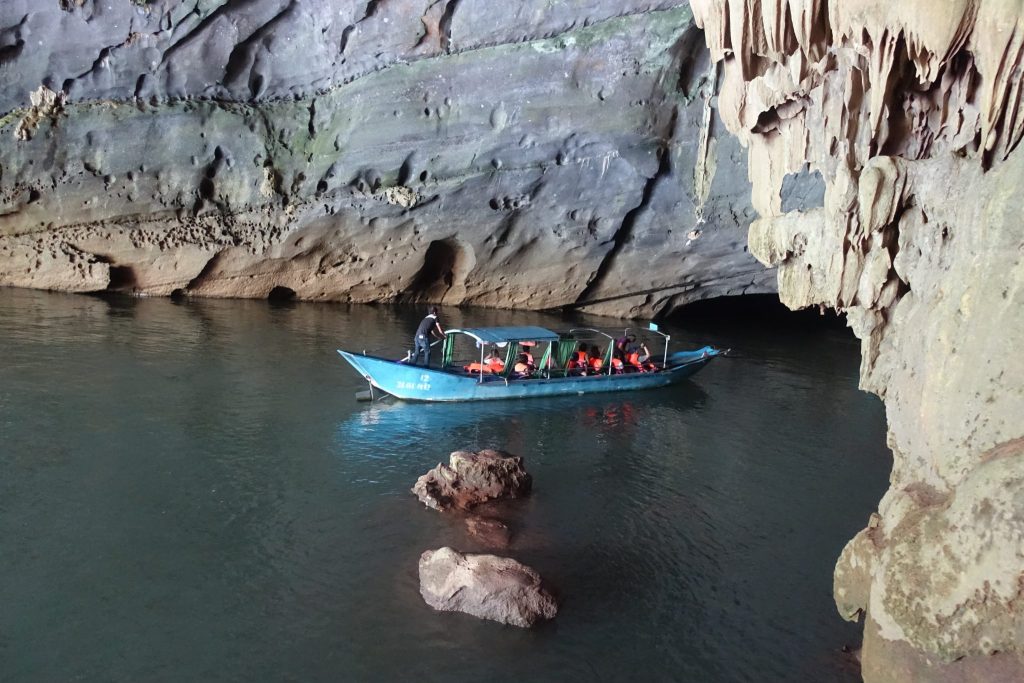 A blue boat carrying some people out of the Phong Nha cave. 