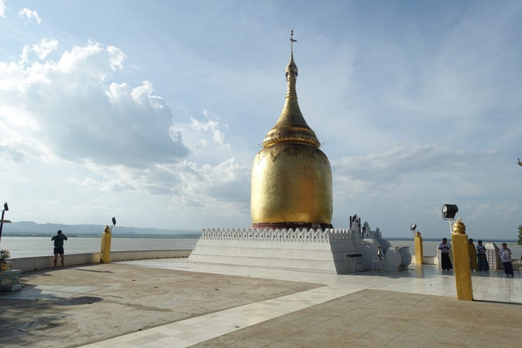The Bupaya pagoda at the bank of the Irrawaddy river is not more than a golden dome and spire. It is in a cornder of a square. You can see a man on the left side taking photos of the river.