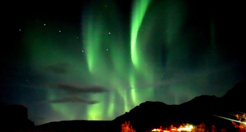 The Northern lights over a mountains with a couple of clouds