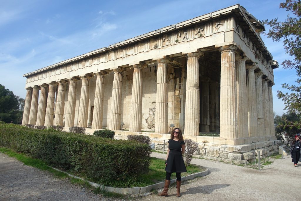 Pilar posing with a black dress in front of the Hephaestus temple. The temple is a reactangular building with a lot of columns