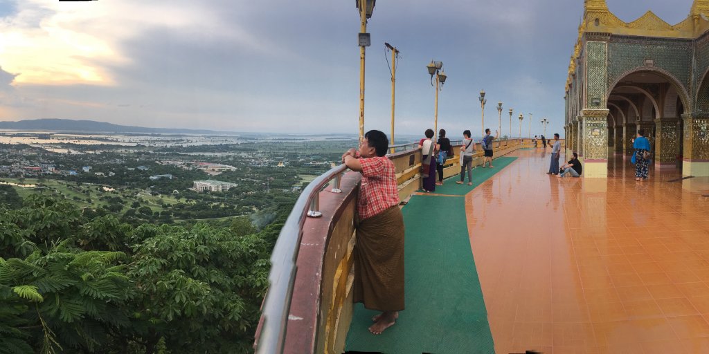 People leaning on the balcony of Mandalay hill watching the sunset.  You can also see a partial view of Mandalay from the above and the river