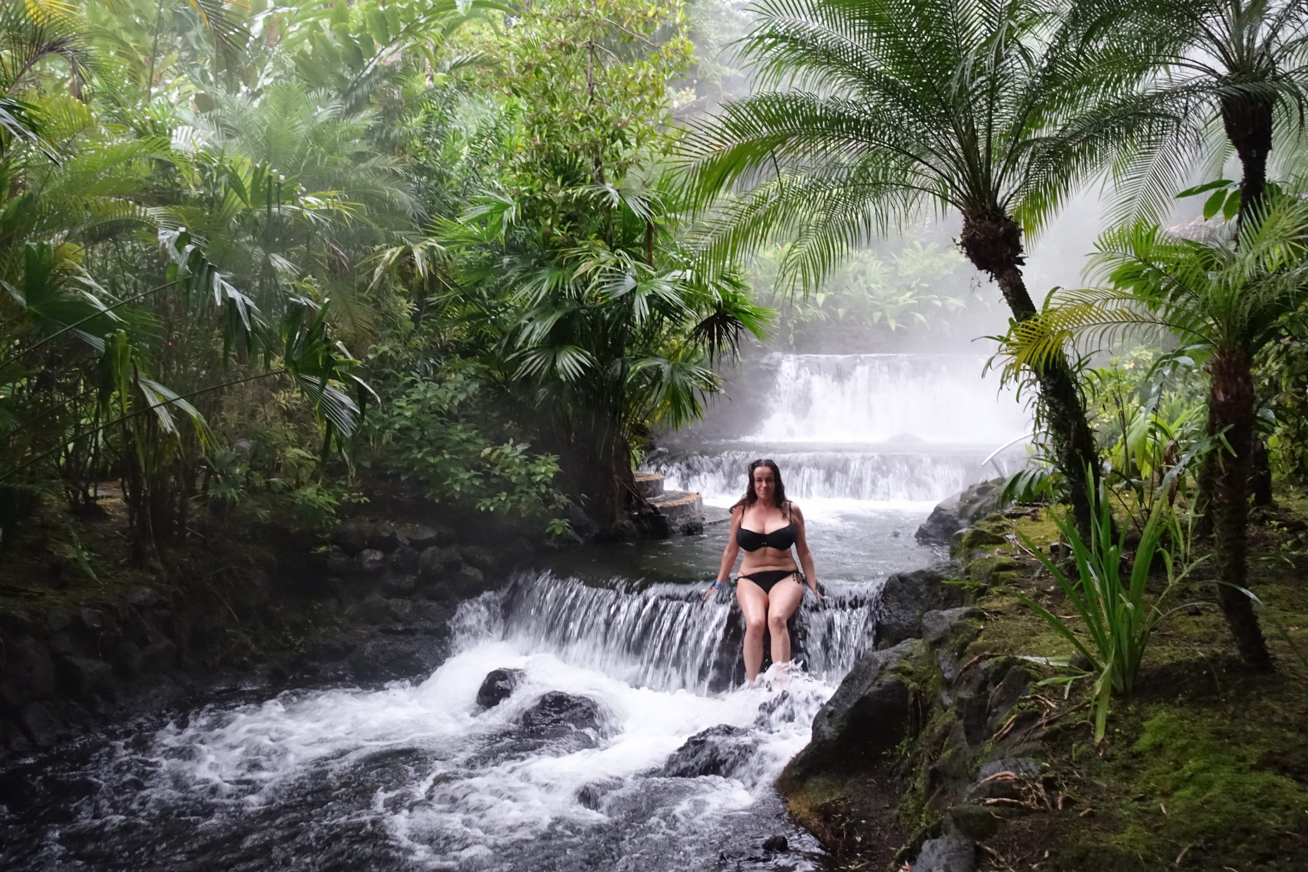 Pilar in Biking sitting in a waterfall in the Tobacon hot springs