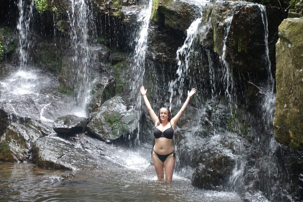 Pilar wearing a black bikini with the arms pointing upwards inside the water at the Rhac Gio waterfall inside the Phong Nha botanical gardens