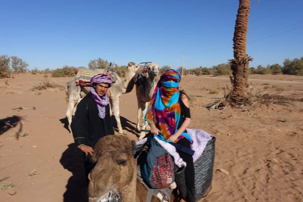 Pilar riding a camel at the entrance of the Sahara desert