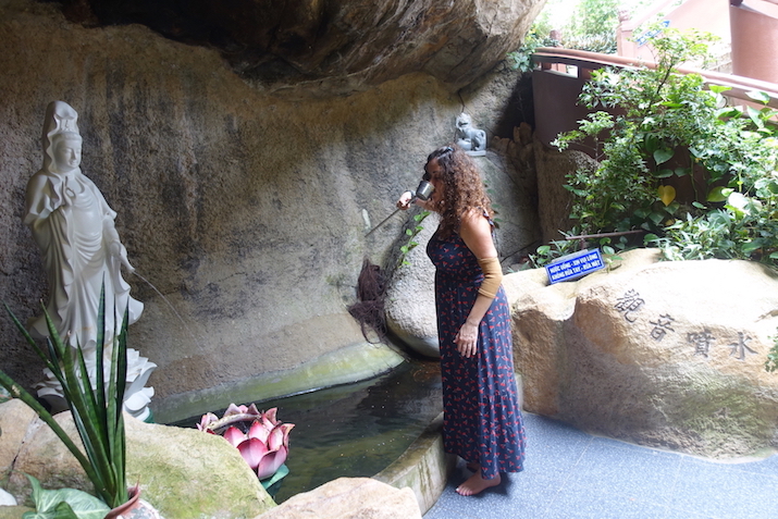 Pilar drinking holy water fro protection at the entrance of the cave pagoda in Chau Doc