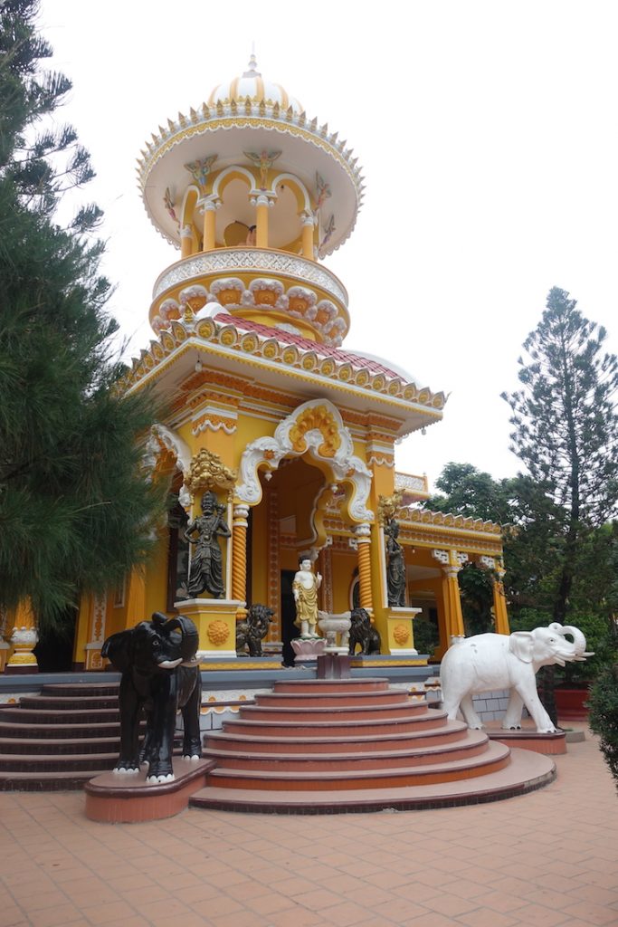 The Tay An temple, It is a yelow color building with white and black elephants at the stair at the entrance. 