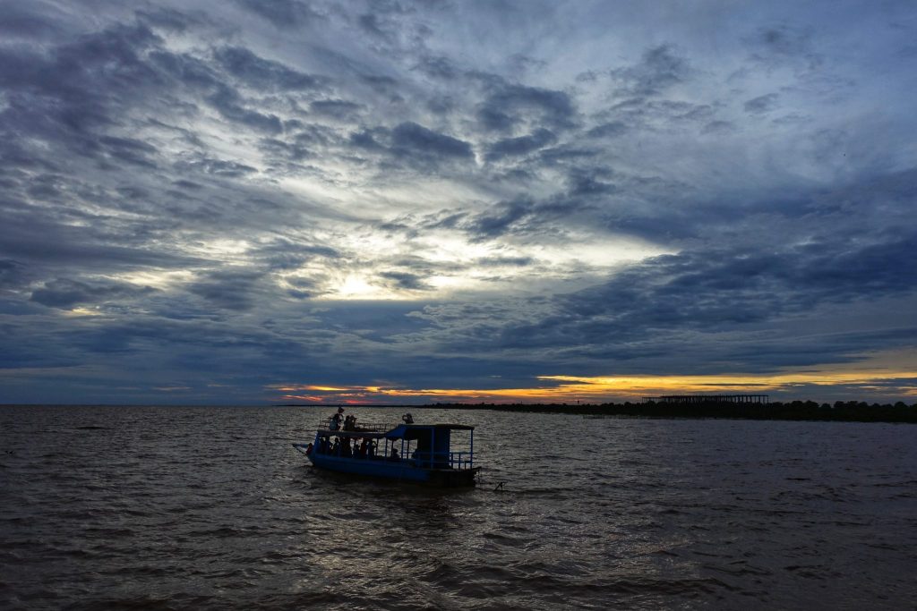 Sunset at Tonle Sap lake. You can see grey clouds and little bit of golden in the horizon. There is a boat also looking black as it is Sunset time on the lake.