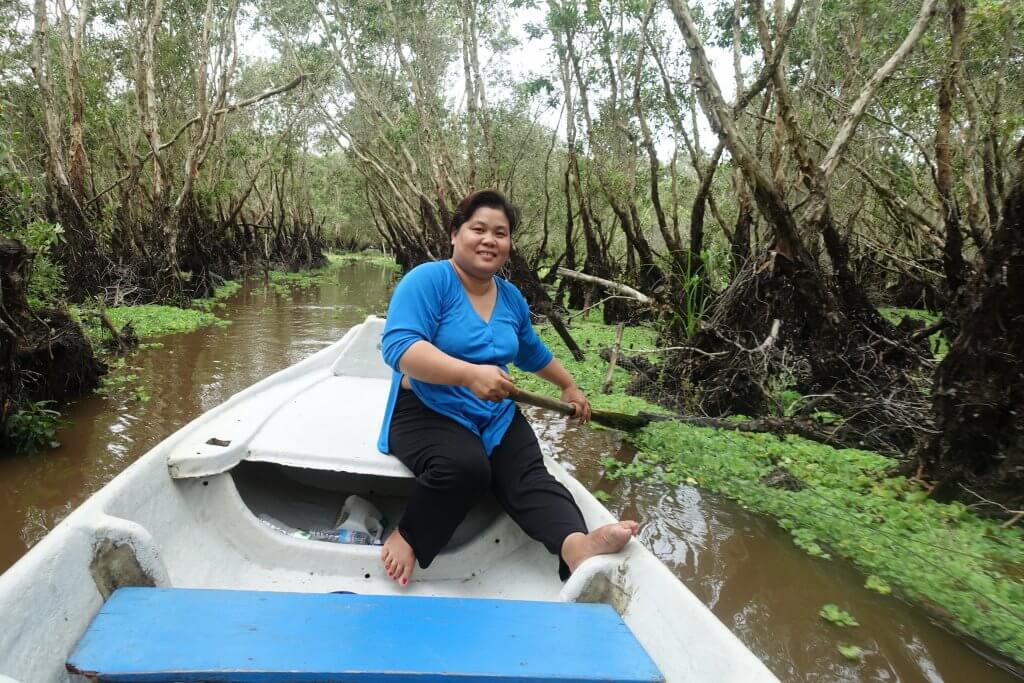 Vui, the rowing woman dress in blue and black rowing through the narrow canal in Trasu forest