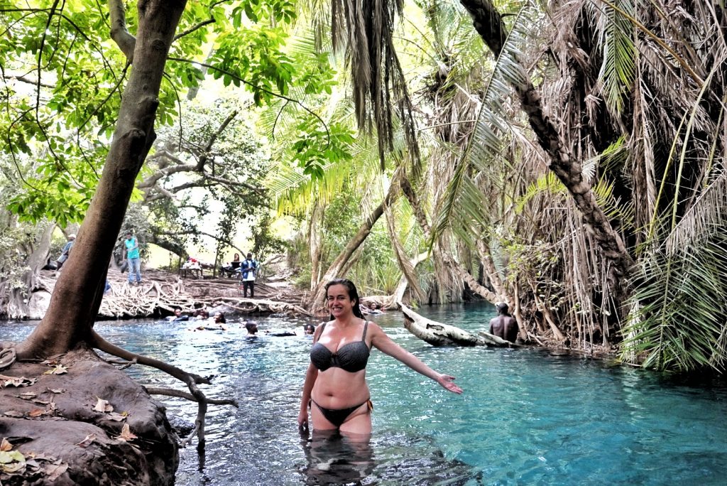 Pilar standing on an underwater tree root in the water at the springs