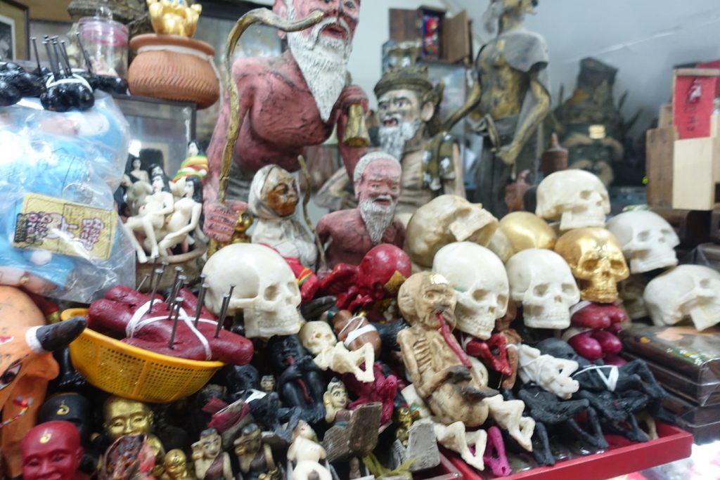 Skulls and other figures that are amulets in a stall in the amulet market in Bangkok