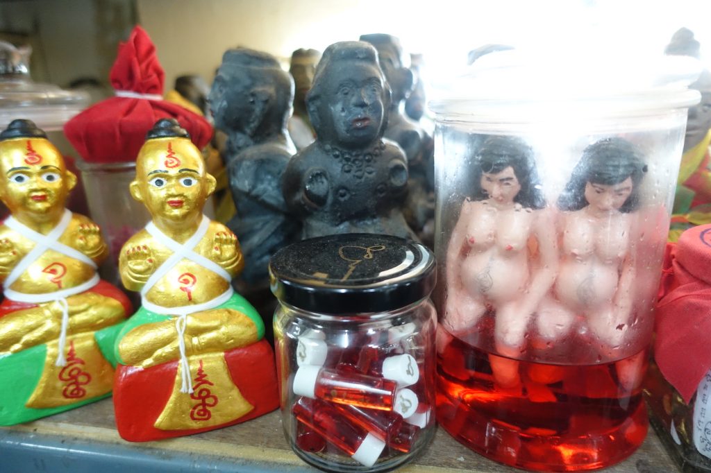 Two preganina women in a bottle, and two black and golden statues that are amulets in the amulet market in Bangkok