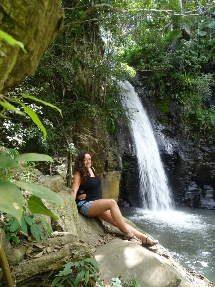 Pilar in the center of Moni sitting on a rock close to the waterfall