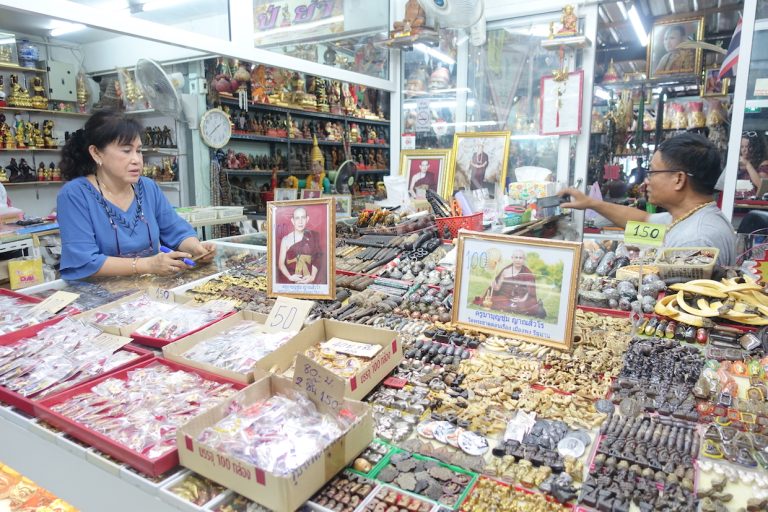 A stall with lots of amulets in the amulet market in Bangkok. The seller is helping a customer