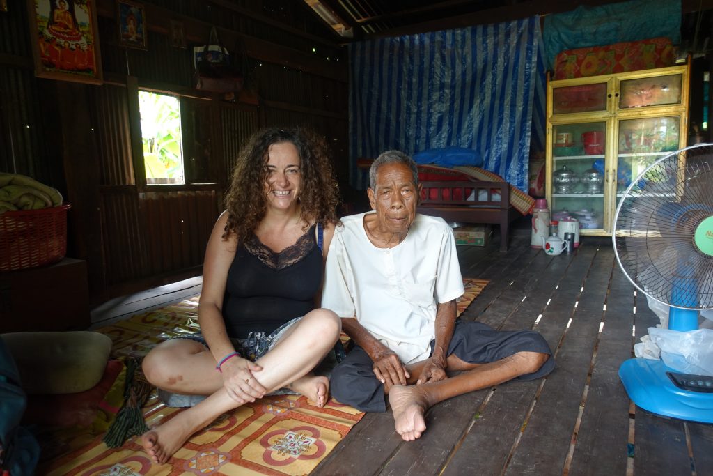 Pilar sitting with an octogenary man in Cambodia in a rice farmers village near Kratie in Cambodia