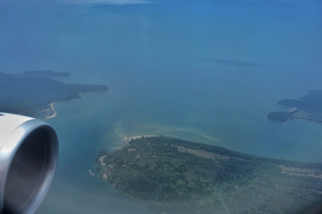 Areial view of the sea and Ranong green coast. You can also see a part of the wings of the plane