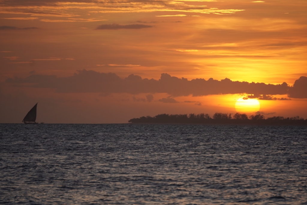 Sunset from Stone Town beach in Zanzibar with Prison island in the horizon and a dhow