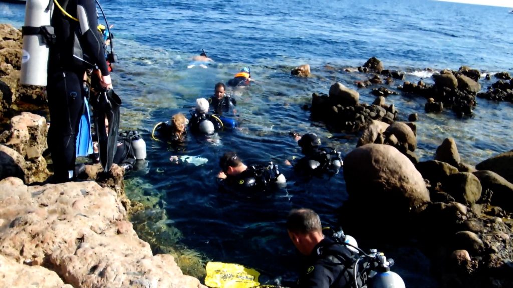 Some divers entering the water through the Bells entry at the Dahab Blue Hole