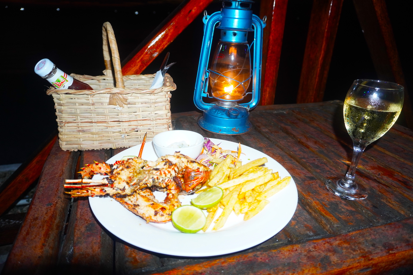 A dish of lobster with chips and a candle on a table at Baraka beach restaurant Zanzibar