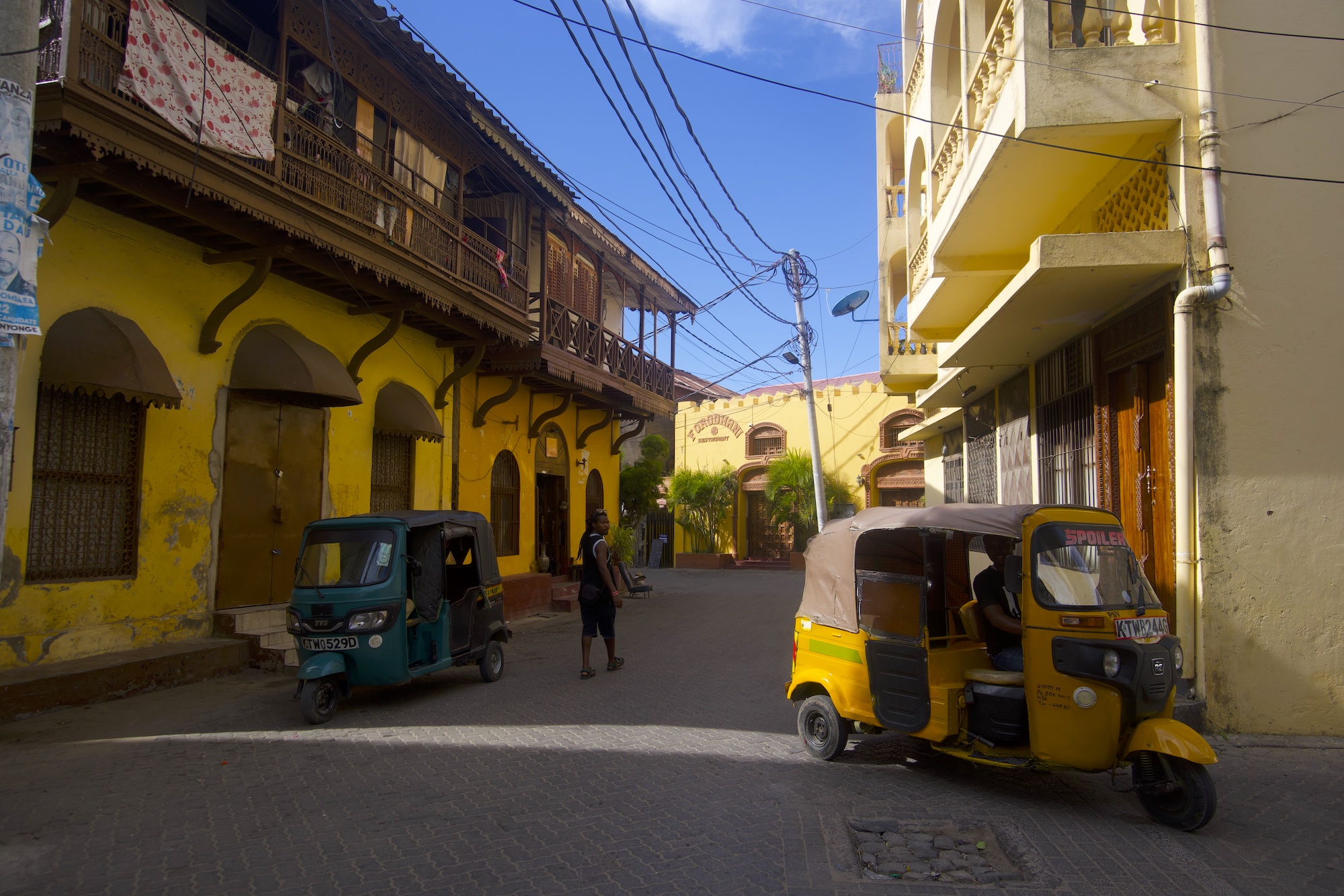 A view of Mombasa Old Town buildings and a yellow Tuk Tuk