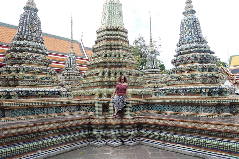 Pilar sitting on top of some chedis at Wat Pho temple in Bangkok. They are beautifully decorated in hues of green, yelos and blue