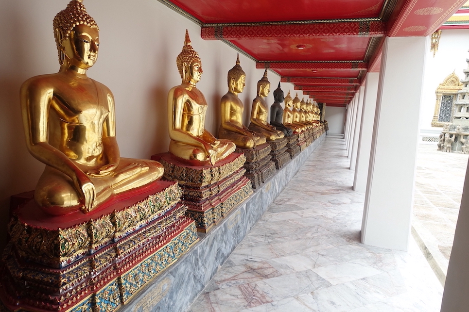 A line of golden Buddhas in an open air corridor in the Wat Pho temple in Bangkok
