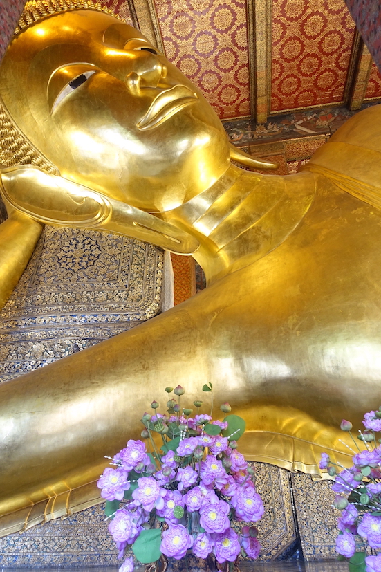 The face of the golden reclining Buddha and some purple flowers