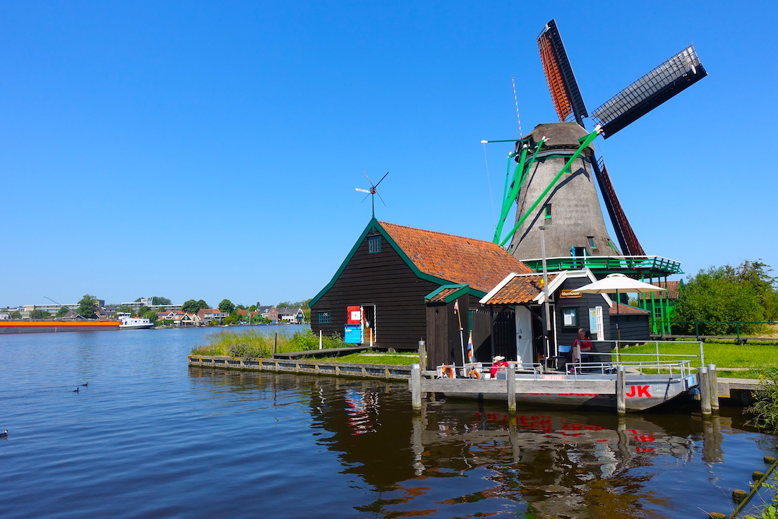 A view of the river Zaan and the ferry stop to cross to the other side and a windmill