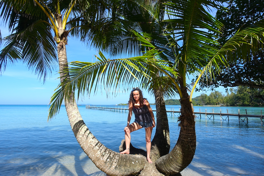 Pilar standing on a palm tree on the Natural resort beach in Koh Kood