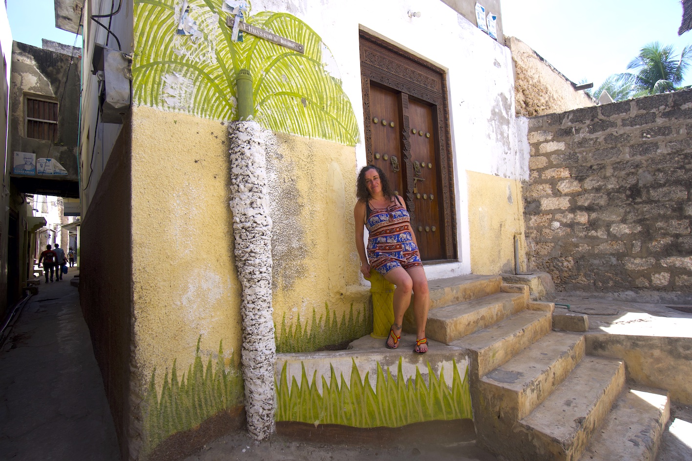 Pilar at the entrance of a house in Lamu Olld Town with a Lamu style door and a palm tree drawing on the wall