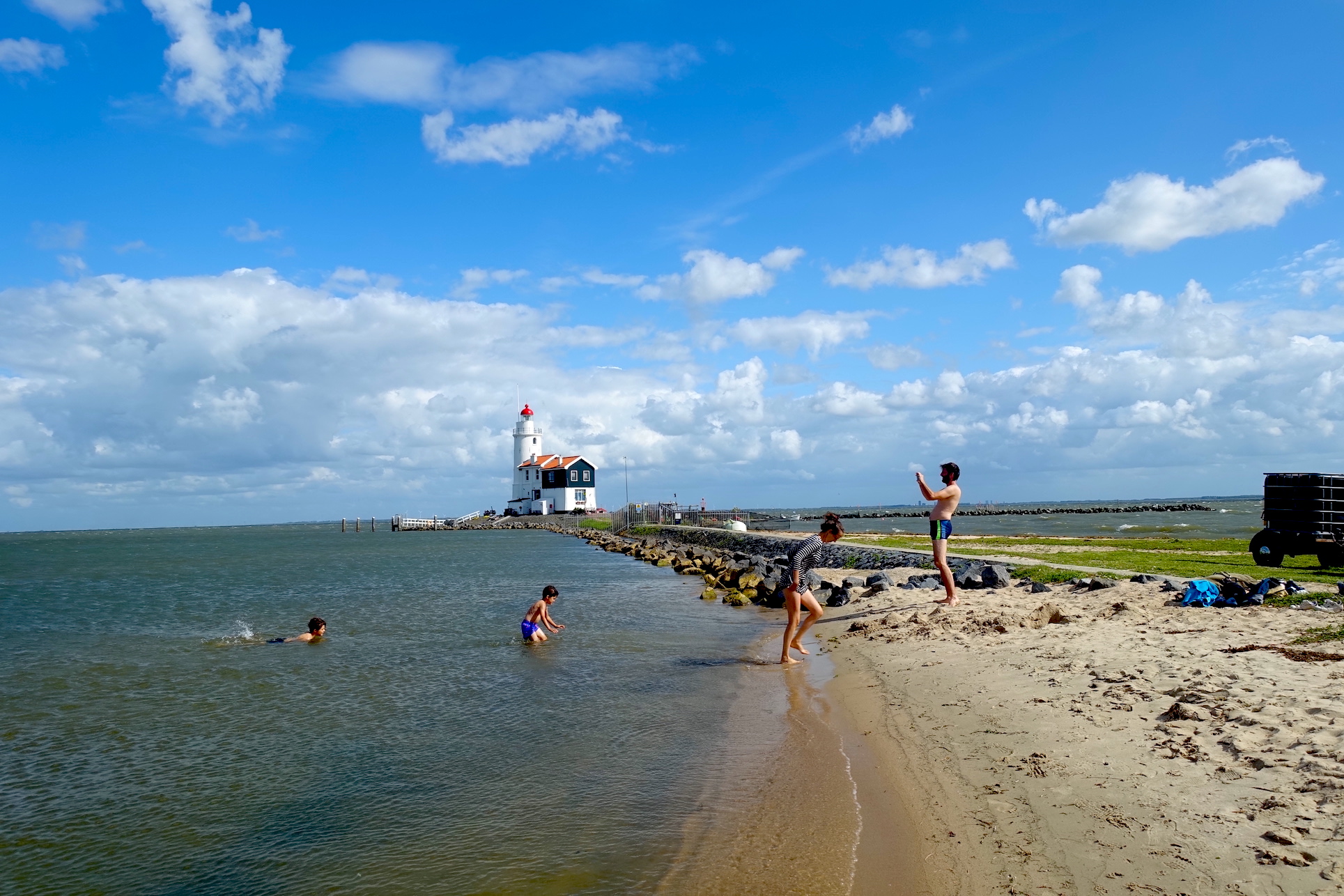 Some swimmers on the Marken beach near Amsterdam and the lighthouse