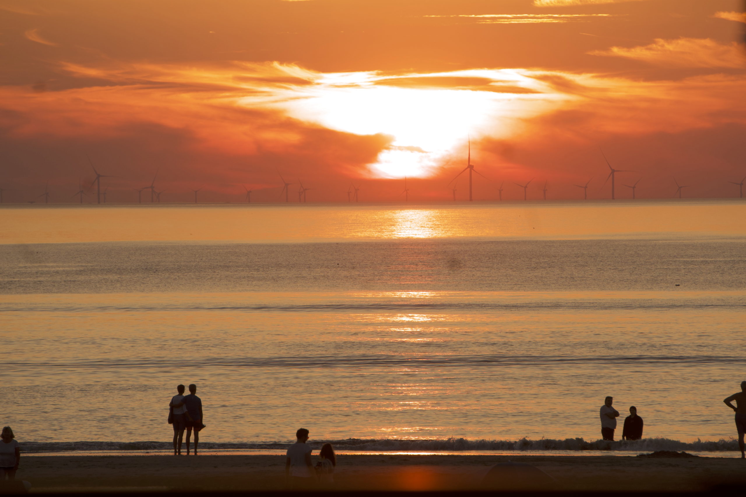 A view of the sunset in Zaanvoort aan zee , one of the closest beaches to Amsterdam,with some people walking on the sea side.
