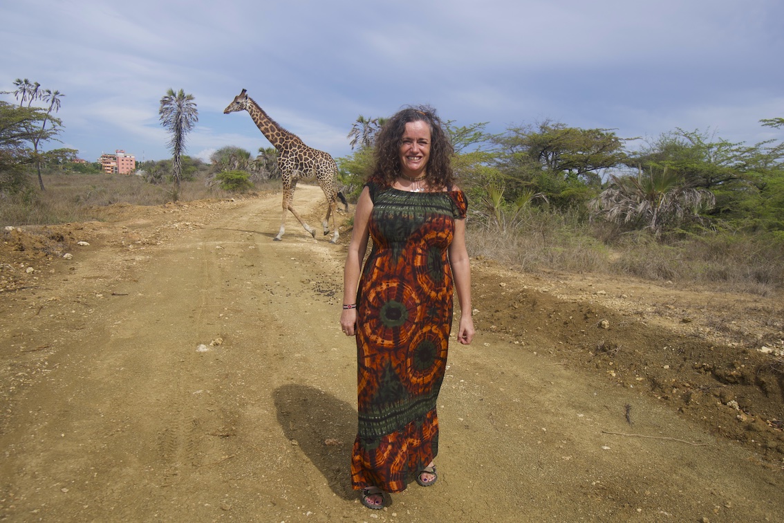 Pilar on a dusty path and a giraffe on the back