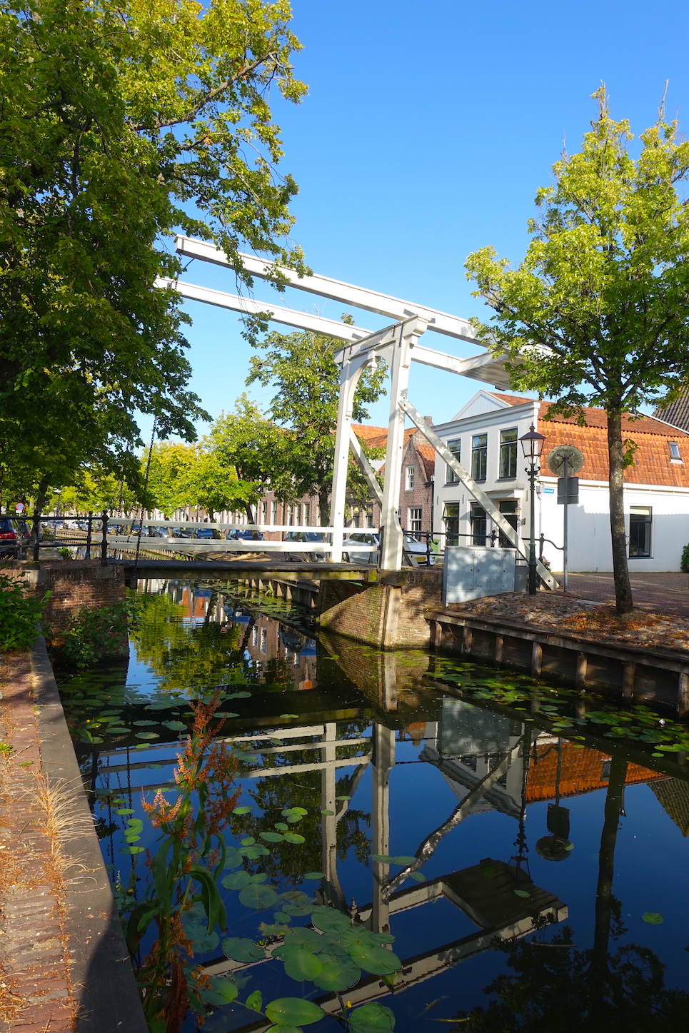 View of an Edam street with a white bridge and reflections on the water canal surface