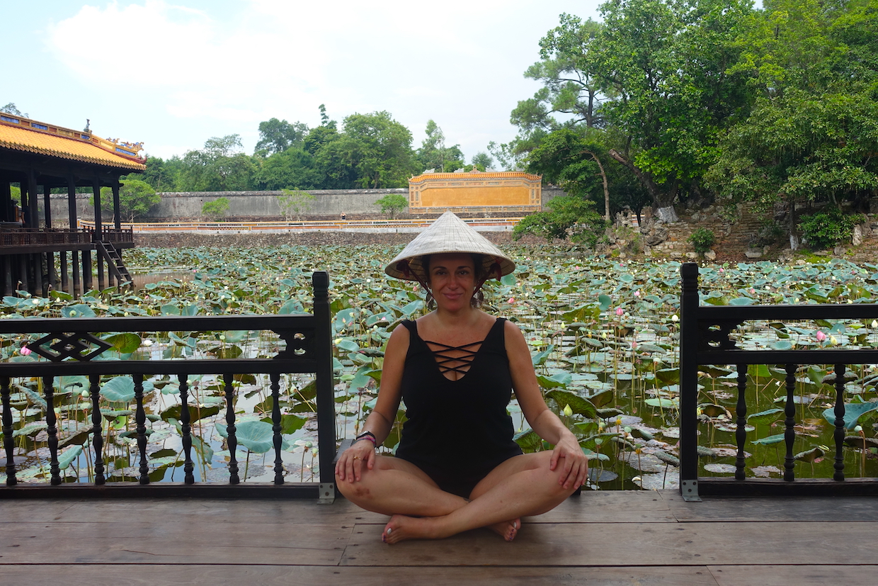 Pilar sitting on a platform in the Tu Duc tomb in Hue, with a lotus flowers pond behind