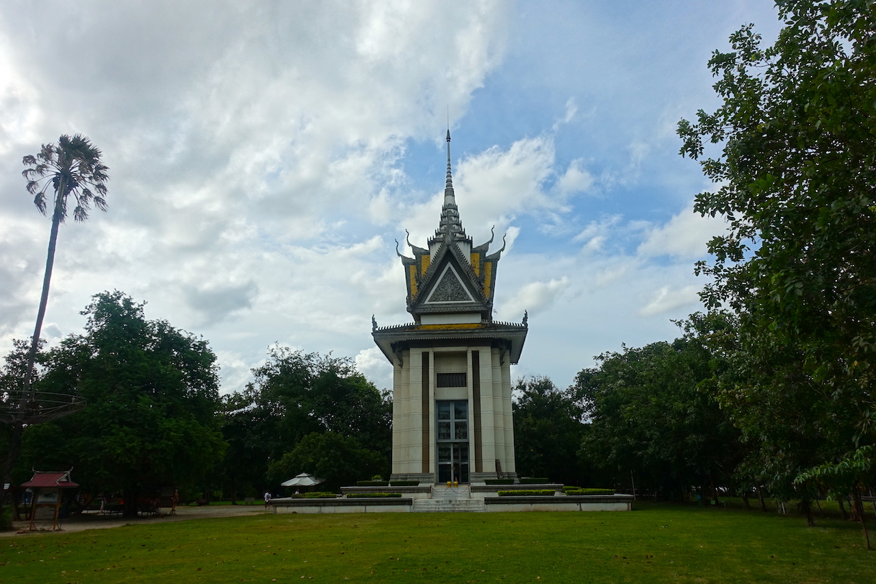 Choeung Ek stupa building with some trees and green grass around
