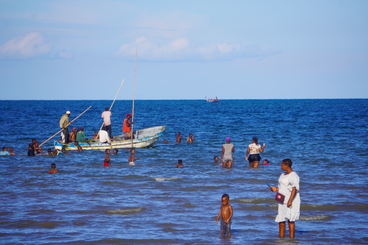 People swimming and a boat at Bagamoyo beach