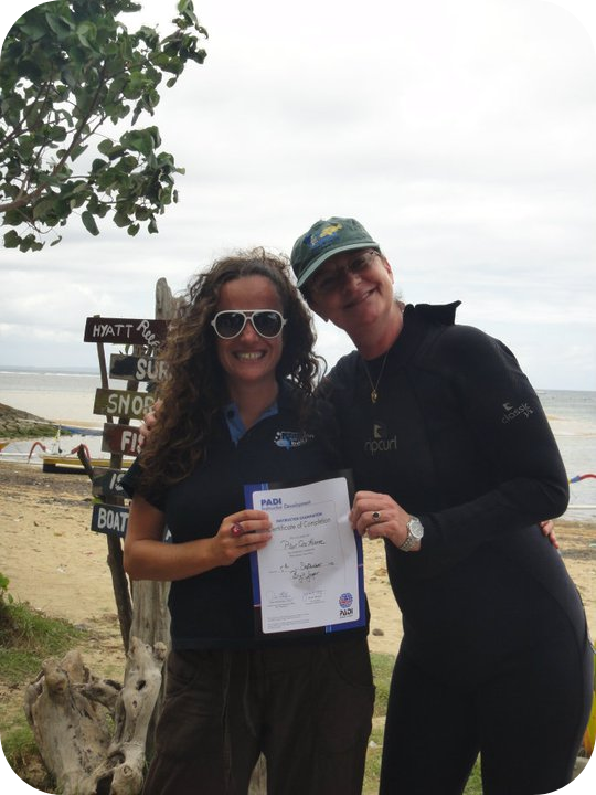 Pilar and the PADI examiner handing the Scuba Diving certification to her