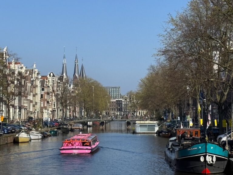 Canal belt view with a pink canal cruise boat and some floating houses