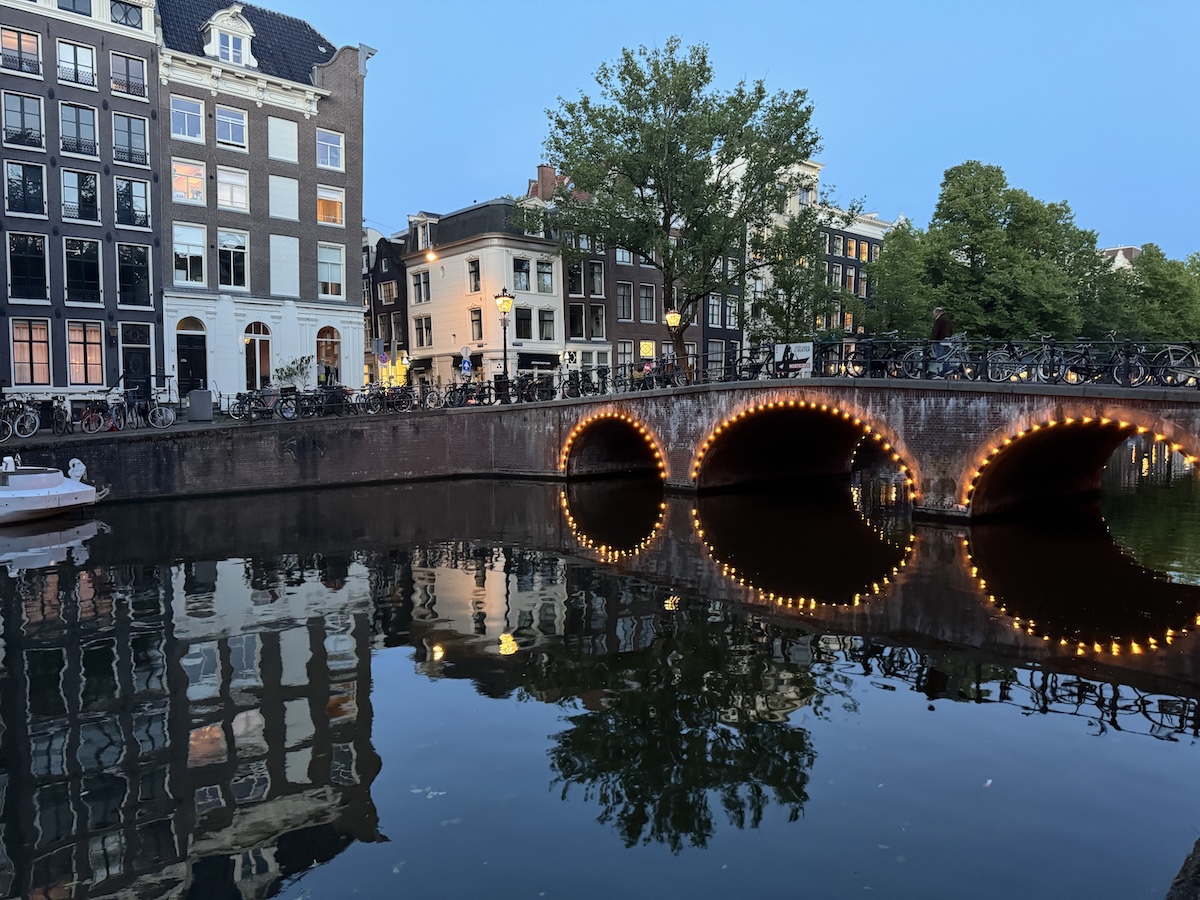 Amsterdam canal bridge with lights reflecting in the water at dusk