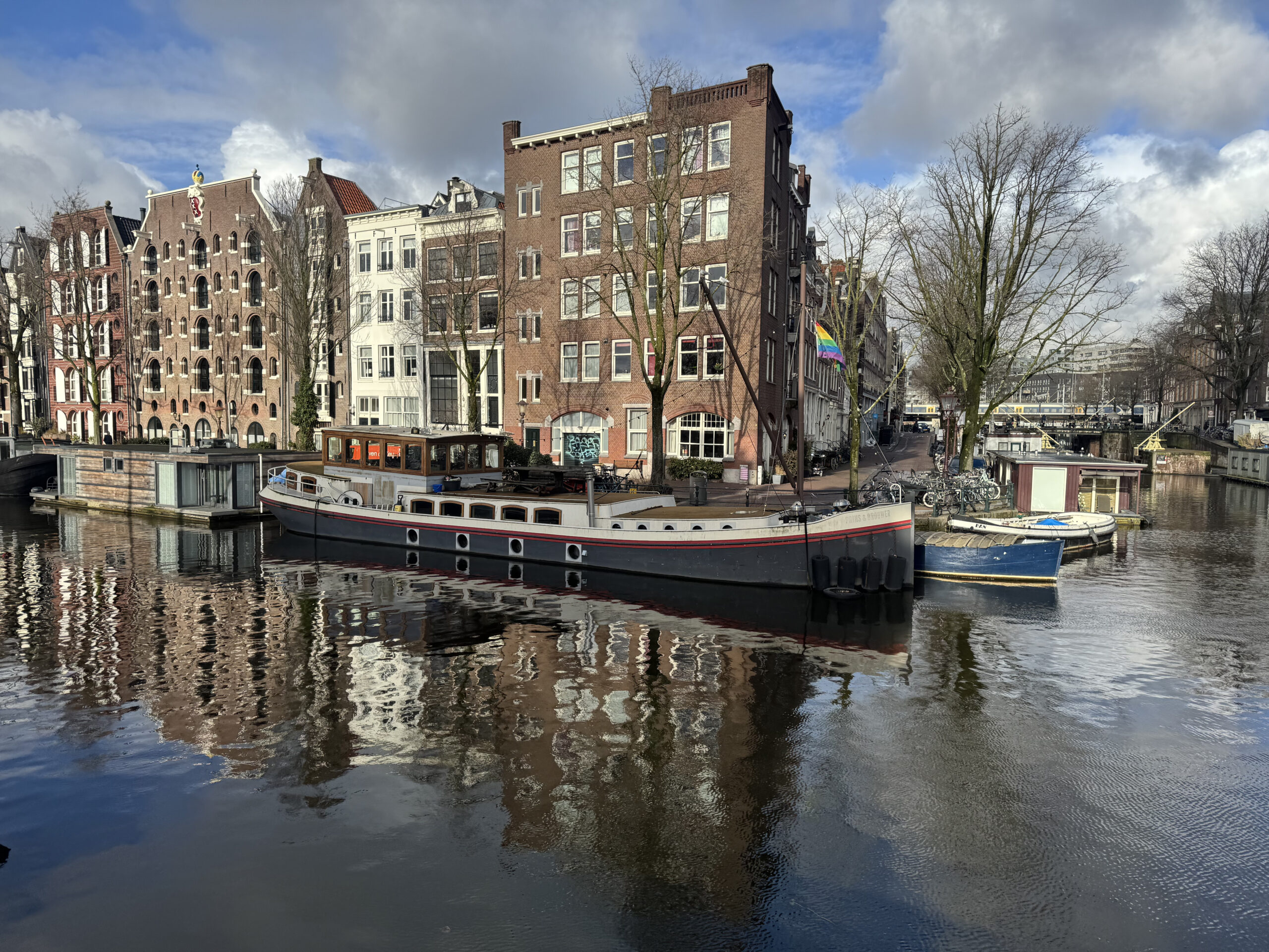 Classic Amsterdam canal with bridge and historic houses under blue sky