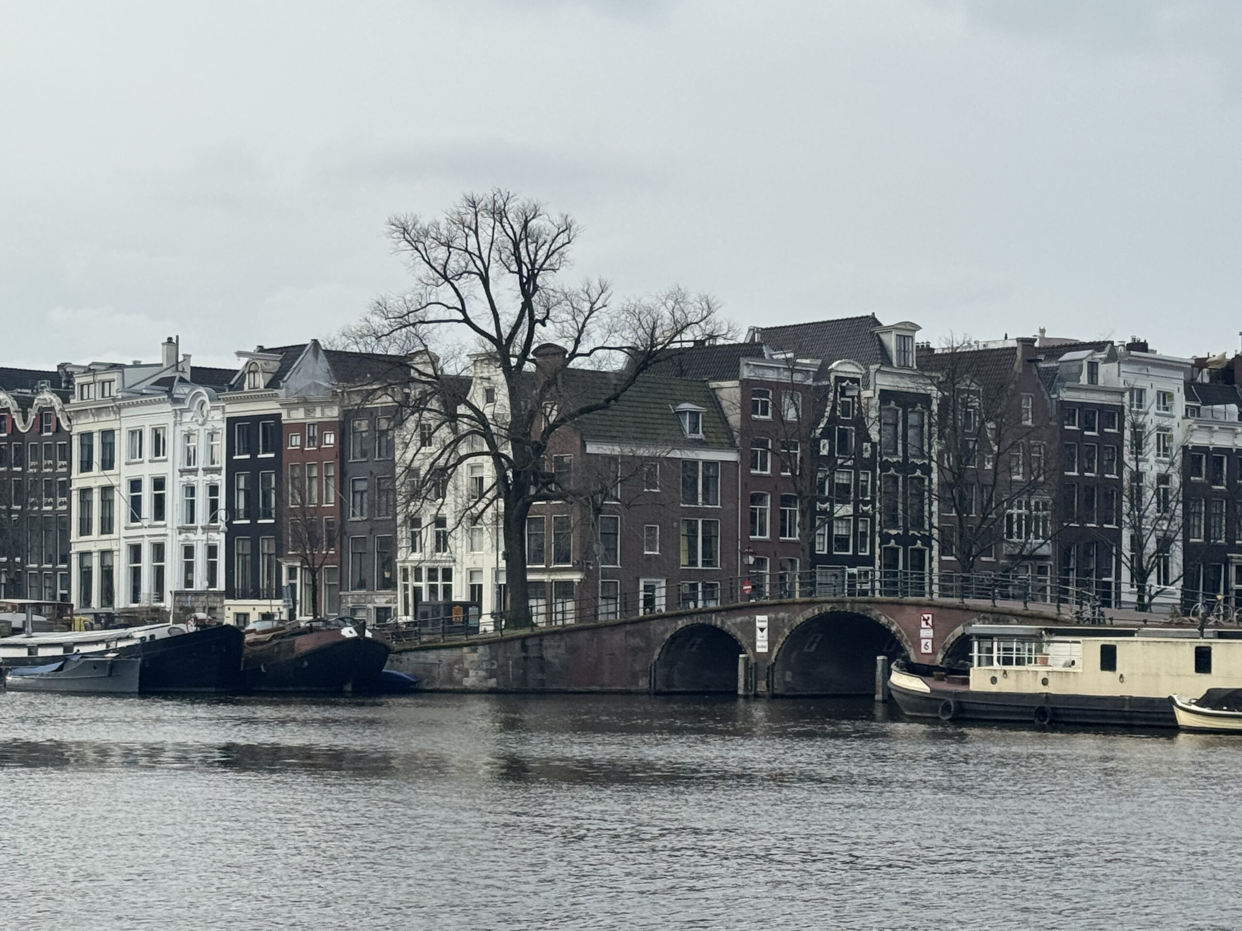 Amsterdam canal with old bridge and houses under a grey sky, linked to the Bullebak legend said to lurk in the water
