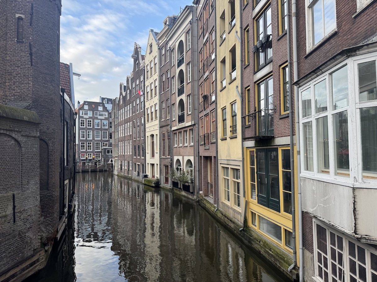 Traditional Amsterdam canal houses reflected in the water along a narrow historic Haunted Amsterdam canal.
