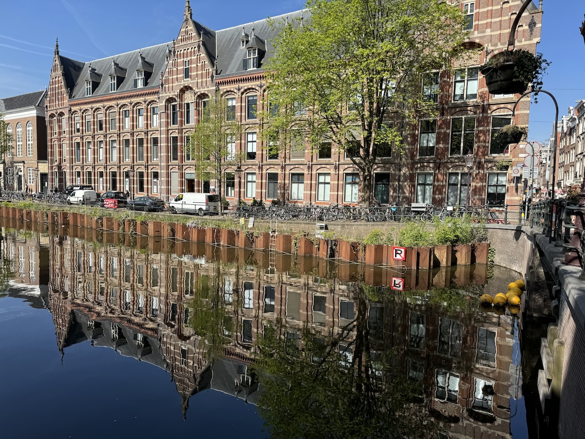 Historic buildings reflected in an Amsterdam canal on a sunny day