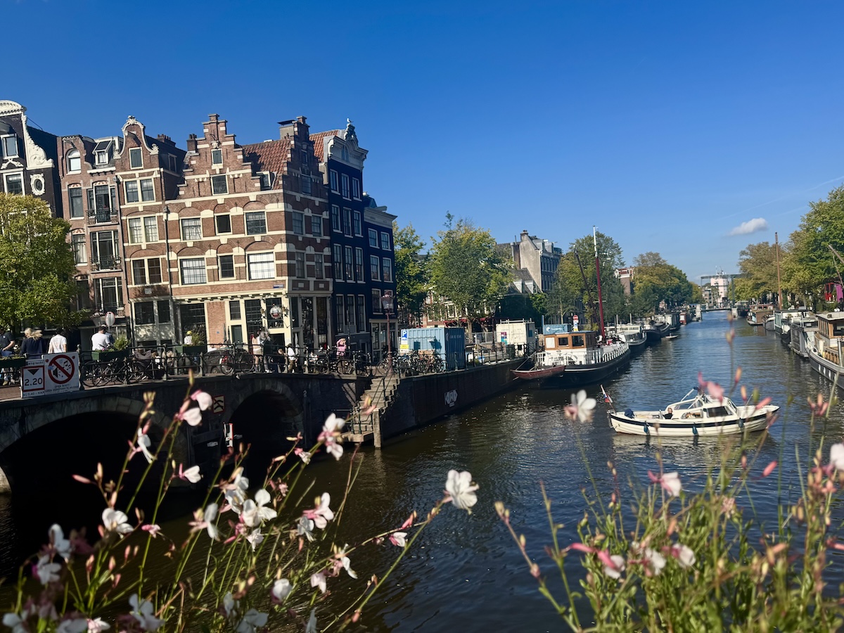 Amsterdam canal view with flowers and a small boat on a sunny day